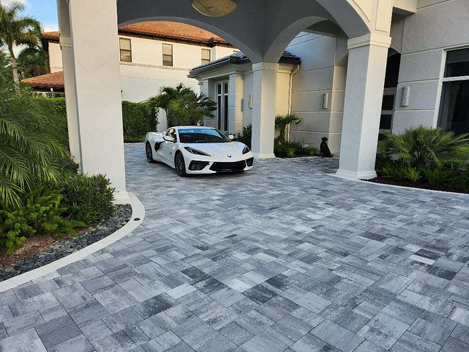 Expensive white car parked on concrete pavers outside mansion